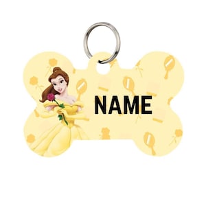 May include: A yellow bone-shaped pet tag featuring a cartoon image of Belle from Beauty and the Beast, holding a rose. The tag has a silver ring and the word "NAME" in black. The background is yellow with repeating mirror and rose graphics.
