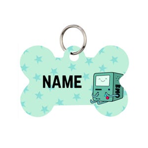 May include: A light blue, bone-shaped pet tag with a repeating star pattern. The tag features the word "NAME" in black block letters and a cartoon character. A silver metal ring is attached for easy attachment to a pet's collar.