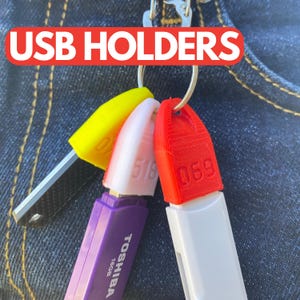 May include: Three USB flash drives with colourful 3D printed protective covers. The drives are attached to a silver keyring. The drives are labelled "059", "518", and "059".
