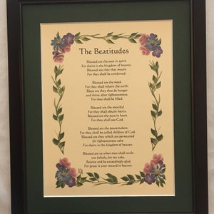 May include: A framed print of the Beatitudes, a Christian text, with a floral border. The text is written in a traditional script and is surrounded by a border of painted flowers in shades of pink, purple, and blue.
