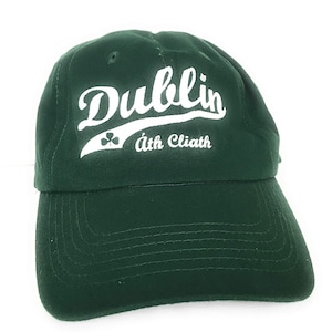 Op de afbeelding: Een groene baseballpet met een wit geborduurd ontwerp met de tekst "Dublin áth Cliath" met een klavertje vier.
