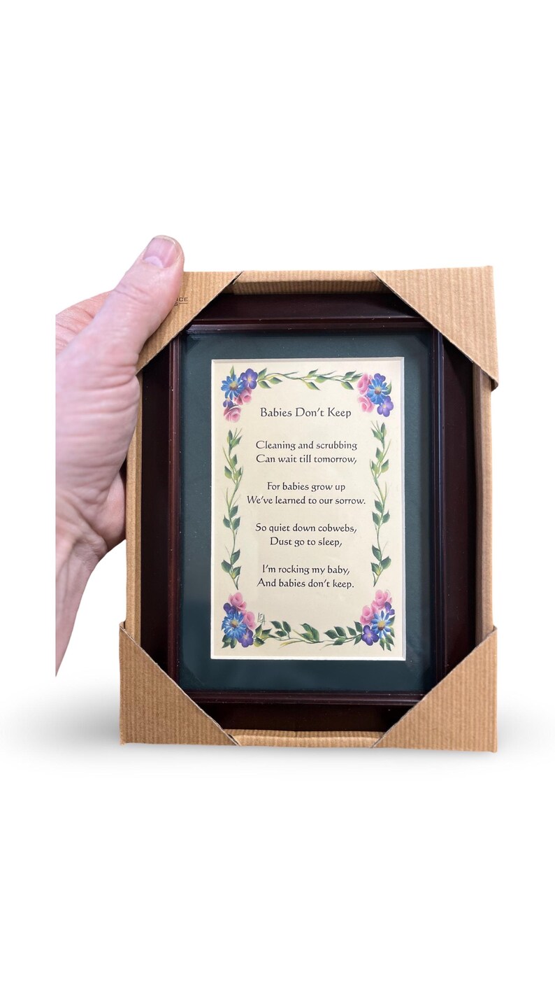 Pode incluir: Um poema emoldurado com uma moldura de madeira escura e um passe-partout verde. O poema &eacute; intitulado "Babies Don't Keep" e est&aacute; escrito em uma fonte caprichosa com ilustra&ccedil;&otilde;es florais. O poema diz: "Limpar e esfregar podem esperar at&eacute; amanh&atilde;, porque os beb&ecirc;s crescem, aprendemos isso com pesar. Ent&atilde;o, sil&ecirc;ncio, teias de aranha, p&oacute; v&aacute; dormir, estou embalando meu beb&ecirc;, e os beb&ecirc;s n&atilde;o ficam."