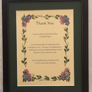 May include: Framed artwork with the words "Thank You" in elegant script. The artwork features a cream-colored background with a floral border of pink and purple flowers and green leaves. The text expresses gratitude.