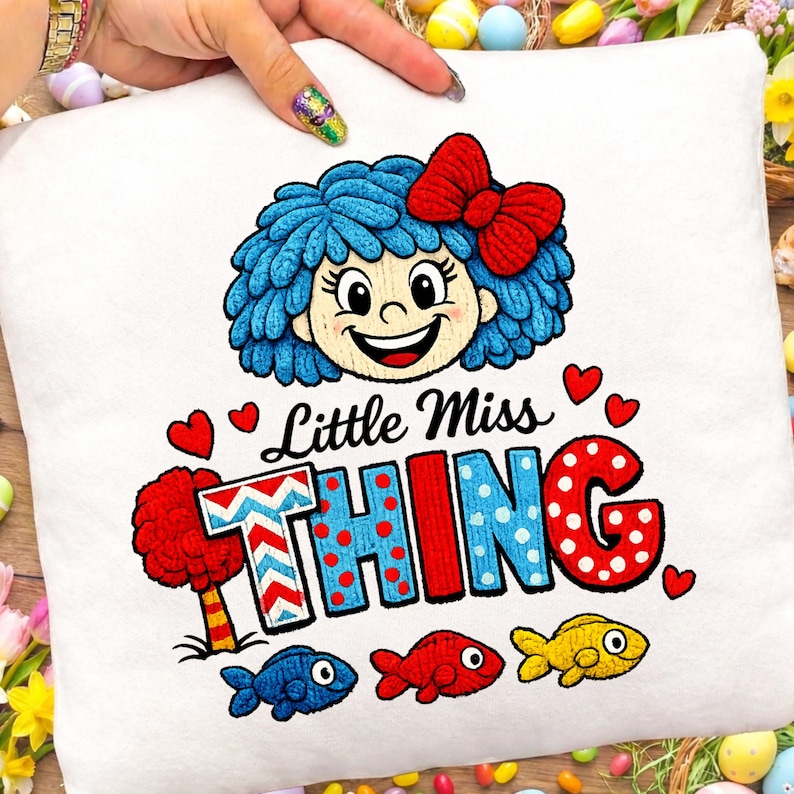 May include: White cushion with a colourful embroidered design. It features a cartoon girl with blue hair and a red bow, and the text "Little Miss THING". The design includes three fish in various colours.