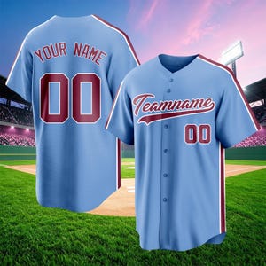 May include: A light blue baseball jersey featuring a button-down front, short sleeves, and maroon trim. The front displays the text Teamname and the number 00, while the back shows the text YOUR NAME and the number 00 in maroon lettering.