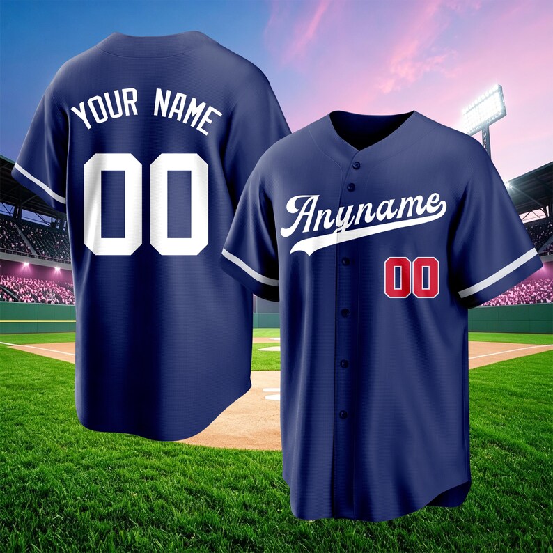 May include: A navy blue baseball jersey featuring a button-down front, short sleeves, and white piping. The front displays the text "Anyname" in white script and the number "00" in red with white outlines. The back shows "YOUR NAME" and "00" in white.