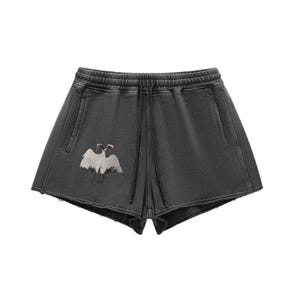 Può includere: Pantaloncini grigio scuro con vita con coulisse e tasche laterali. I pantaloncini presentano una grafica di due gru bianche con dettagli rossi. Aspetto usurato.