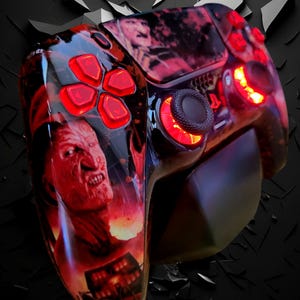 Peut inclure: Une manette de jeu vidéo noire et rouge avec un design personnalisé représentant un monstre rouge et noir. La manette a des lumières rouges qui brillent sur les boutons et à l'arrière.