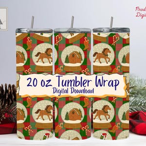 May include: A set of three 20 oz. tumbler wraps with a festive design. The wraps feature a repeating pattern of snow globes with horses, barns, and Christmas elements on a red and green plaid background. The text "20 oz Tumbler Wrap Digital Download" is displayed.