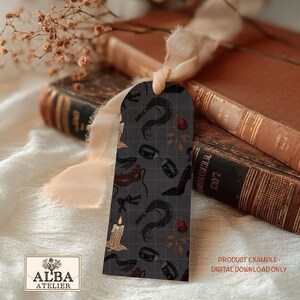 Puede incluir: Un marcap&aacute;ginas gris oscuro con un patr&oacute;n de l&aacute;tigos, tacones altos, esposas y rosas. Tambi&eacute;n se ven una vela encendida y el texto "ALBA ATELIER". Ejemplo de producto de descarga digital.