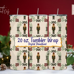 May include: Three 20 oz tumbler wraps featuring a repeating pattern of nutcrackers, berries, and foliage on a cream backdrop. The text "20 oz Tumbler Wrap Digital Download" is displayed. The tumblers have a silver straw.
