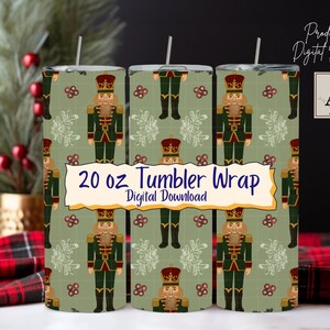 May include: Three 20 oz tumbler wraps feature a repeating pattern of nutcrackers in green, red, and gold. The design includes the text "20 oz Tumbler Wrap Digital Download". The background is a light green colour.