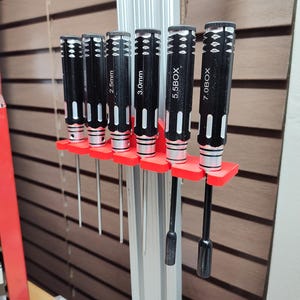 May include: A red plastic screwdriver holder with six screwdrivers hanging from it. The screwdrivers are black with silver accents and have the following sizes printed on them: 2.5mm, 3.0mm, 5.5BOX, 7.0BOX.