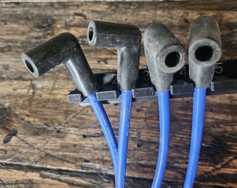 May include: Four blue spark plug wires with black rubber boots. The wires are attached to a black plastic holder with numbers 2, 3, 4, and 5 printed on it. The text "Pro-Spark Professional Manufacturer" is printed on the holder.