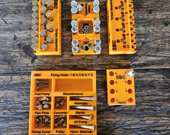 May include: Orange plastic organizers with compartments for small parts, labeled "SBC" and "Torque Sequence". The organizers contain various bolts, screws, and other hardware. The organizers are labeled with the firing order for a small block Chevrolet engine.