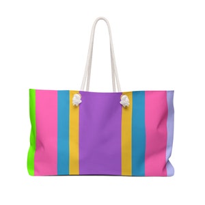 May include: A colorful striped tote bag with white rope handles. The bag has stripes of green, pink, blue, yellow, and purple.