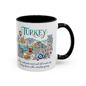 May include: A white ceramic mug with a black handle and rim, featuring a colorful illustration of Turkey. The design includes the word Turkey, a bridge, a mosque, a hot air balloon, tea, baklava, and an evil eye charm, with the text: Where continents meet and old winds sing, Turkey shines with a timeless spring.