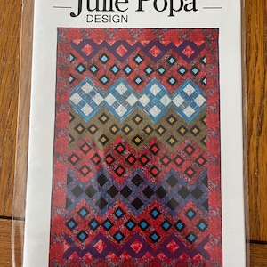 May include: A quilting pattern titled "Mosaics" by Julie Popa Design. The pattern features a colorful geometric design with red, blue, black, and yellow squares and diamonds.