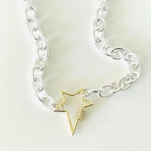 Puede incluir: Un collar de cadena de plata con un cierre en forma de estrella dorada.