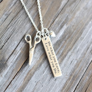 May include: A silver necklace with a charm that says "Do what you love, Love what you do." The charm is attached to a silver chain with a pair of silver scissors and a small silver heart.