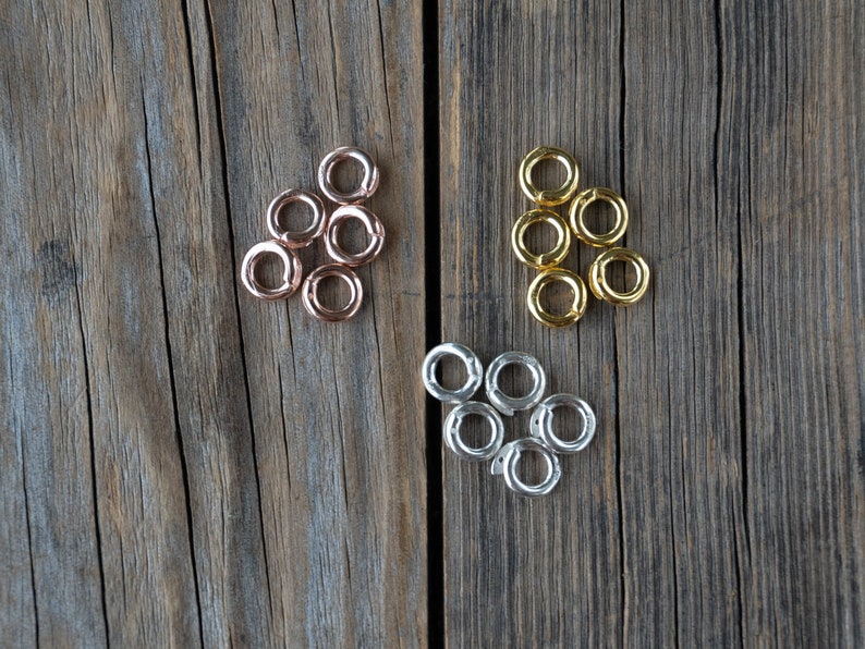 Pu&ograve; includere: Un set di sei anelli a salto in tre diverse finiture: oro rosa, oro e argento. Gli anelli sono disposti in tre gruppi di due su una superficie di legno.