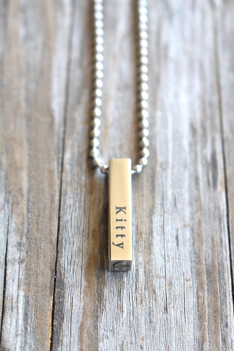 May include: A silver chain necklace with a silver bar pendant engraved with the name "Kitty".