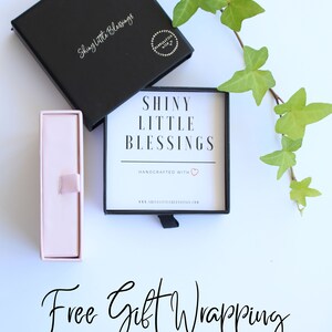 K&ouml;nnte beinhalten: Eine schwarze Box mit dem Text "Shiny Little Blessings" und eine rosa Box mit einem Band. Der Text "Free Gift Wrapping ~ Ships Next Day ~" steht unter den Boxen.