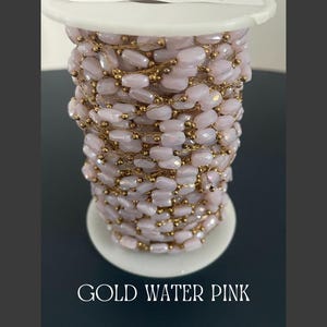 May include: A spool of gold-toned wire wrapped with light pink, faceted beads. The beads are strung together with gold wire. The text "GOLD WATER PINK" is at the bottom of the image.
