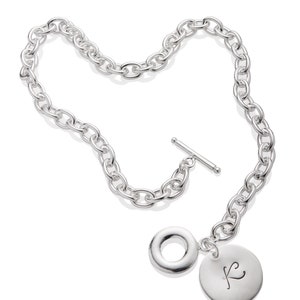 Puede incluir: Un collar de cadena de plata con un dije redondo grande y un dije redondo m&aacute;s peque&ntilde;o con la letra "K" grabada.