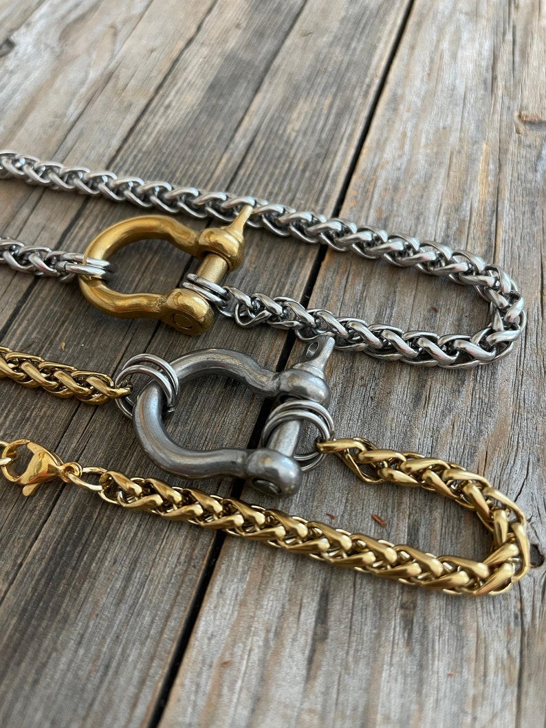 Pu&ograve; includere: Tre collane a catena diverse con finitura oro, argento e ottone. Ogni collana presenta una chiusura unica a forma di anello rotondo grande con un perno.