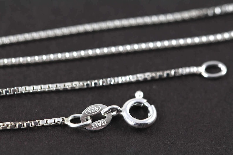 May include: A silver chain necklace with a lobster clasp and a tag that reads "925 ITALY".