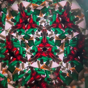 K&ouml;nnte beinhalten: Ein Kaleidoskopbild mit einem symmetrischen Muster aus roten und gr&uuml;nen Formen. Der Hintergrund ist wei&szlig; mit einer subtilen Textur.