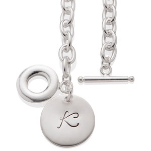 Puede incluir: Collar de cadena de plata con cierre de palanca y un dije redondo con la letra K grabada.