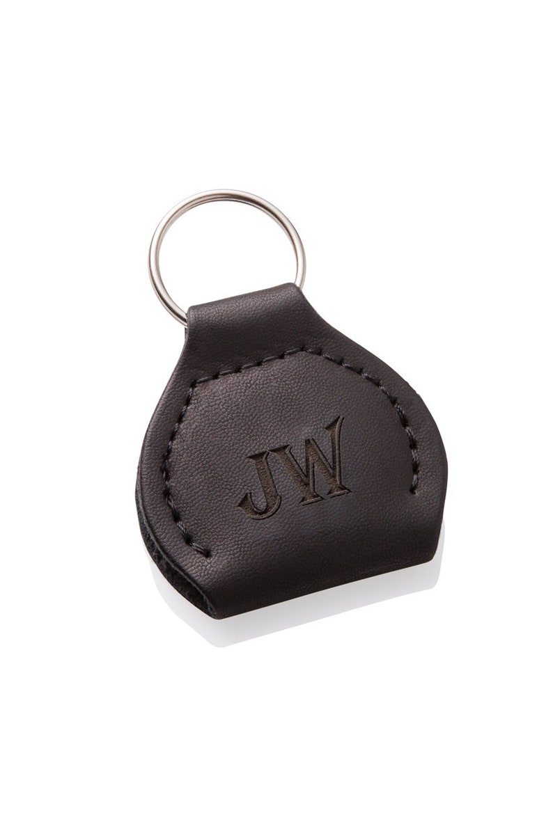 May include: A brown leather keychain with a silver key ring. The keychain has the initials "JW" embossed on the front.