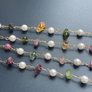 Puede incluir: Primer plano de varias hebras de joyer&iacute;a delicada. Cada hebra presenta peque&ntilde;as perlas blancas y brillantes intercaladas con piedras preciosas de colores de forma irregular en tonos verdes, amarillos, rosas y morados. Las cuentas est&aacute;n ensartadas en finas cadenas de oro.
