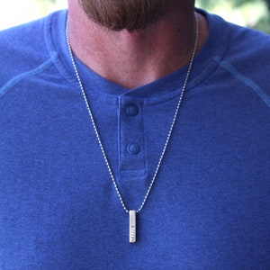 May include: A silver chain necklace with a silver bar pendant engraved with the word "Kiley".