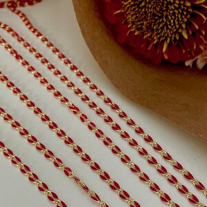 May include: Four strands of red and gold chain, with the red enamel on the outside of the chain links.
