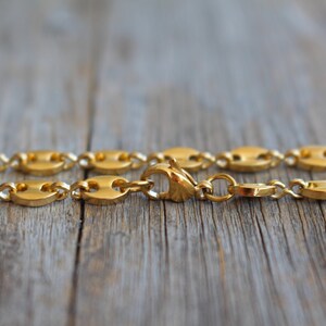 May include: A gold chain necklace with a mariner link design. The chain is made of metal and has a shiny finish.