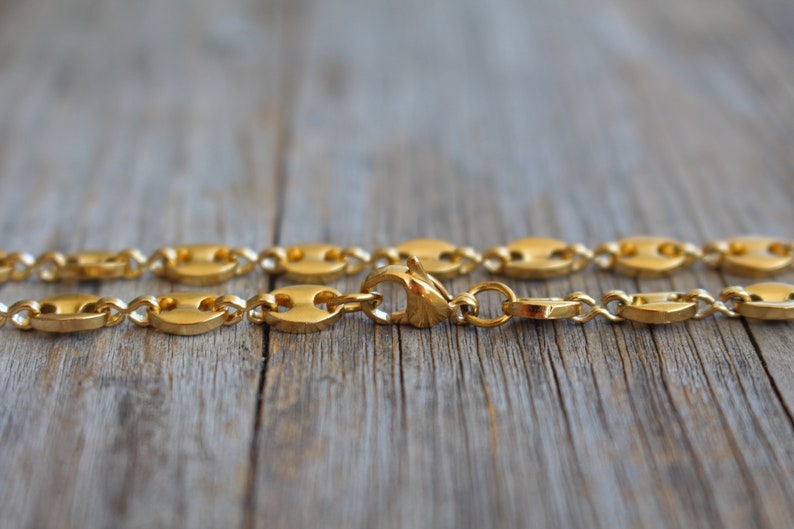 May include: A gold chain necklace with a mariner link design. The chain is made of metal and has a shiny finish.
