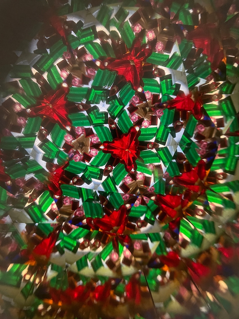 K&ouml;nnte beinhalten: Ein Kaleidoskopbild mit einem sich wiederholenden Muster aus roten Sternen und gr&uuml;nen Rechtecken. Der Hintergrund ist wei&szlig; mit einer leichten Unsch&auml;rfe.
