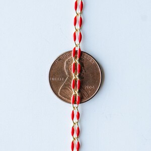 May include: A red and gold chain with a penny in the middle. The penny is dated 2004 and has the words "LIBERTY" and "IN GOD WE TRUST" on it.