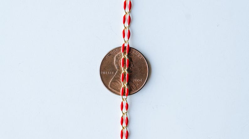 May include: A red and gold chain with a penny in the middle. The penny is dated 2004 and has the words "LIBERTY" and "IN GOD WE TRUST" on it.
