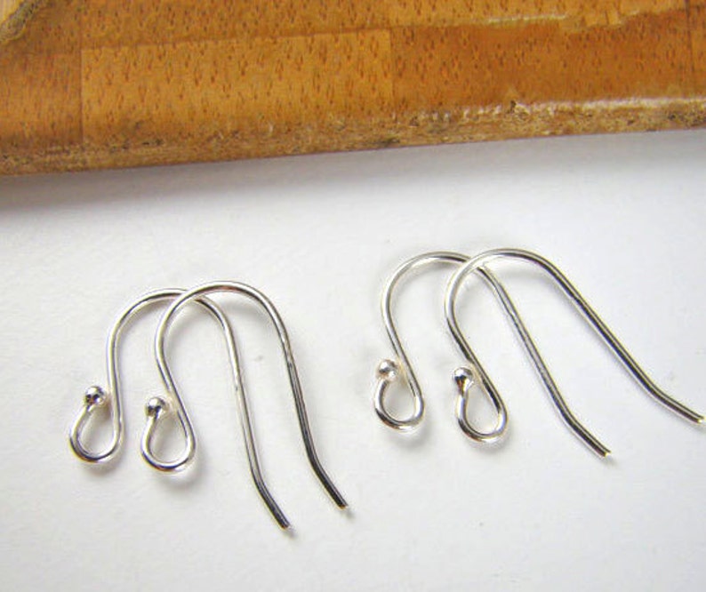 May include: Four silver earring hooks with a small ball at the top of each hook.