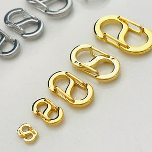 May include: A set of six gold-colored and two silver-colored key chain clips. The clips are in various sizes and are shaped like a figure eight.