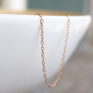May include: A delicate rose gold chain necklace. The chain is made of small, linked oval shapes.