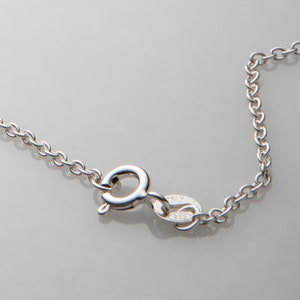 Puede incluir: Un collar de cadena de plata con un cierre de langosta y una etiqueta que dice "ITALY 925".