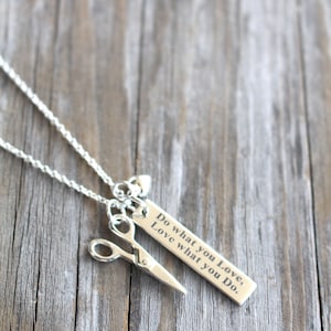 May include: Silver necklace with a pair of scissors charm and a rectangular tag that reads "Do what you Love, Love what you Do."