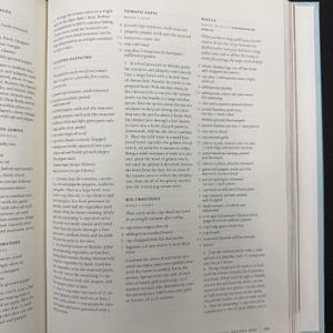 May include: Open cookbook page with recipes for Tomato Aspic, Big Croutons, and Paella. The page features text and instructions for preparing various dishes, with ingredients and measurements.