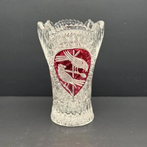 May include: A clear glass vase with a textured, diamond-cut pattern. A red heart-shaped design with two birds is featured on the front. The vase has a scalloped rim and is suitable for displaying flowers.