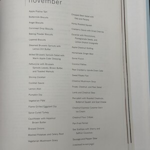 May include: A page from a cookbook featuring a list of recipes for the month of November. The recipes include dishes like Apple Praline Tart, Shrimp Cocktail, and Chestnut Mushroom Soup. The text is in black font.